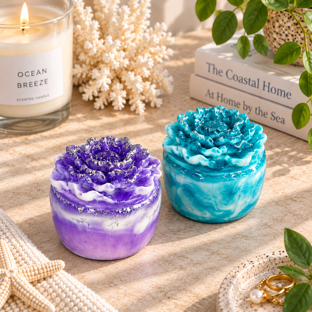 Two handmade rose-lidded trinket boxes in purple and white marble and turquoise and white marble, displayed on a beige tabletop with coastal décor.
